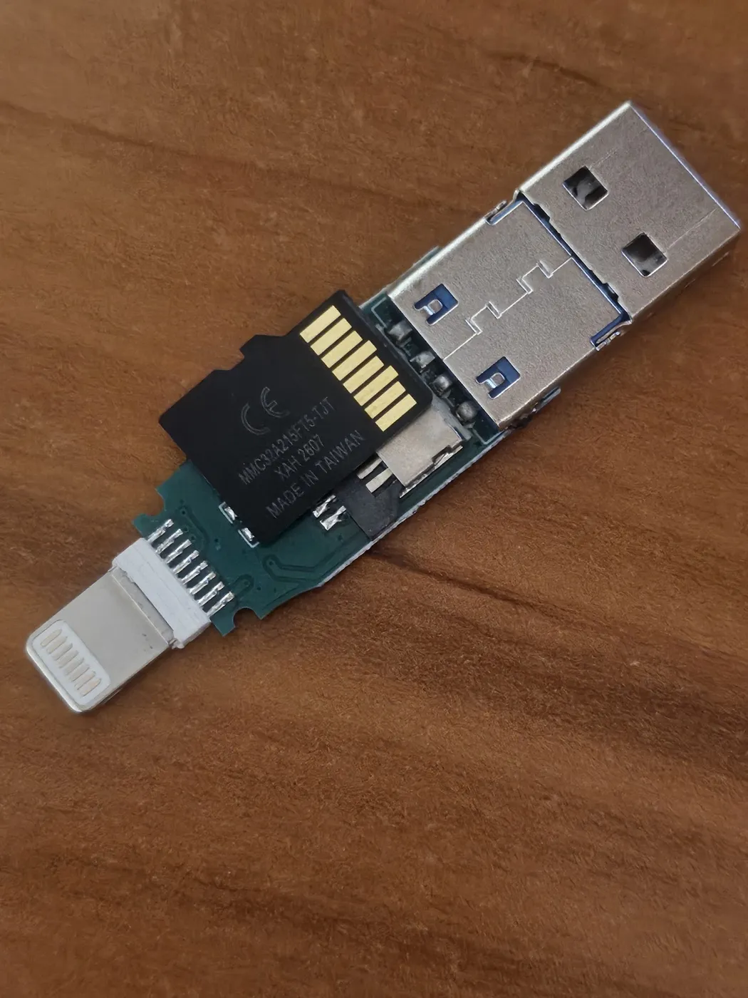 USB 포트와 Lightning 커넥터가 있는 다중 어댑터 장치의 분해된 부품들을 갈색 배경에서 촬영한 사진입니다.